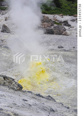 Geothermal fumarole field on a volcano slope in the Kuril Islands. Hot steam vents and bright yellow sulfur deposits. Geothermal fumarole field on a volcano slope in the Kuril Islands. Hot steam vents and bright yellow sulfur deposits. 135455738