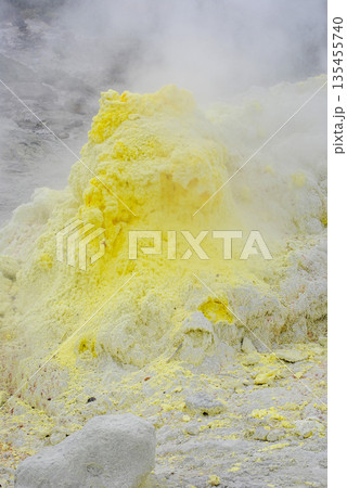 Geothermal fumarole field on a volcano slope in the Kuril Islands. Hot steam vents and bright yellow sulfur deposits. 135455740