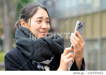 スマホを使用するマフラーをした女性 135455852