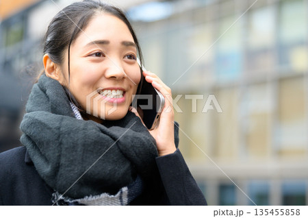 スマホを使用するマフラーをした女性 135455858