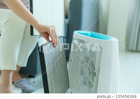 Woman changing filter of home air purifier. 135456168