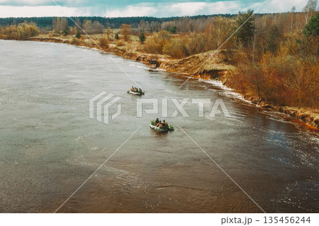 Men Dressed As US American Soldiers Of USA Infantry Of World War II carry out rafting on rubber boats In spring Autumn Day. Group of Soldiers people are preparing to disembark. Aerial view elevated 135456244