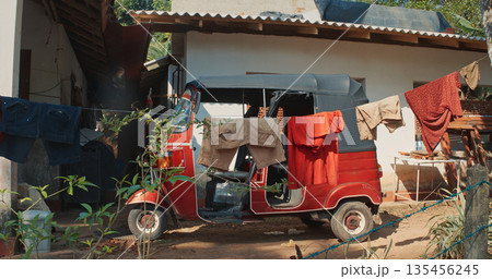 Red Tuk Tuk Parked with Laundry at Traditional Sri Lankan Residence Red Tuk Tuk Parked with Laundry at Traditional Sri Lankan Residence 135456245