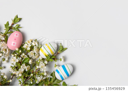 Easter colored painted eggs and blooming spring cherry branches on gray background in shape of frame with space for text and greetings. Easter and spring concept. Spring background Easter colored painted eggs and blooming spring cherry branches on gray background in shape of frame with space for text and greetings. Easter and spring concept. Spring background 135456929