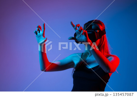 Woman Interacting With Virtual Reality Interface Using Both Hands, Advanced VR Technology, Gaming and Metaverse Experience Woman Interacting With Virtual Reality Interface Using Both Hands, Advanced VR Technology, Gaming and Metaverse Experience 135457087