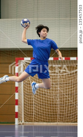 空中で体をひねりシュートを放つハンドボール部の女子高校生 135457503