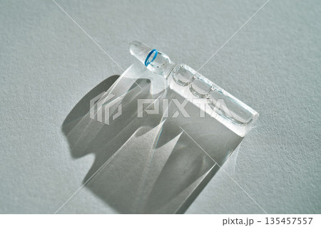 Ampoule casting clear shadow on gray background Ampoule casting clear shadow on gray background 135457557