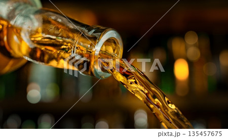Pouring Whiskey from Bottle . Stream of Golden Liquid Flows on a Pub 135457675