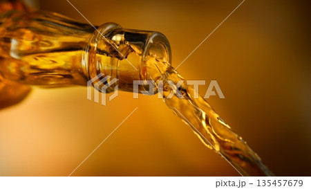 Pouring Whiskey from Bottle . Stream of Golden Liquid Flows on Orange Background Pouring Whiskey from Bottle . Stream of Golden Liquid Flows on Orange Background 135457679