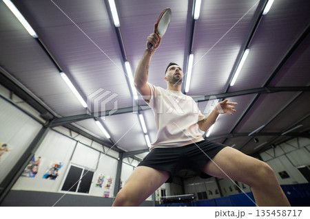 Male athlete playing table tennis hitting serve Male athlete playing table tennis hitting serve 135458717