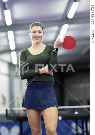Young woman smiling while holding table tennis paddle Young woman smiling while holding table tennis paddle 135458755