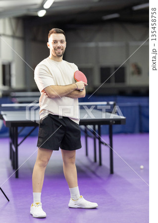 Young man smiling holding table tennis paddle indoors 135458758