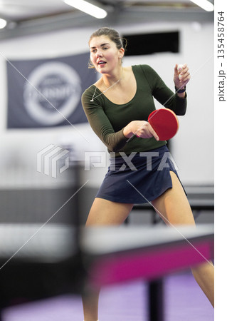 Young woman playing table tennis preparing for serve 135458764