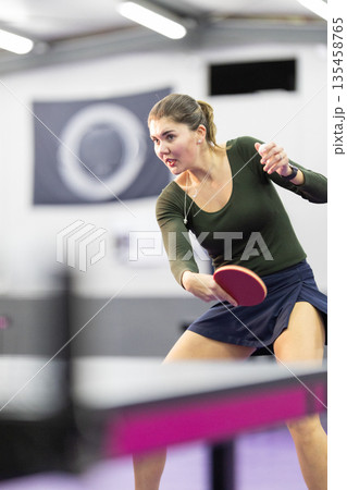 Young woman playing table tennis with intense focus Young woman playing table tennis with intense focus 135458765