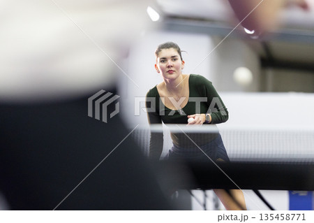 Woman concentrating playing table tennis in indoor court Woman concentrating playing table tennis in indoor court 135458771