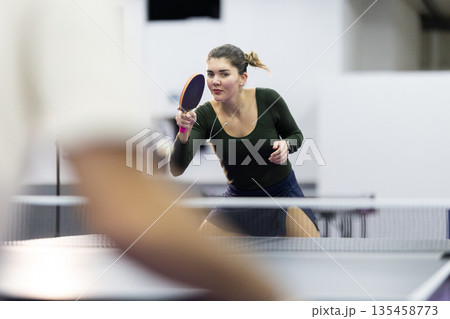 Young woman playing table tennis, concentrating on the game 135458773
