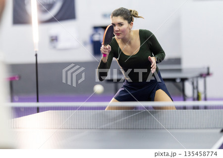 Young woman playing table tennis hitting ball with paddle 135458774