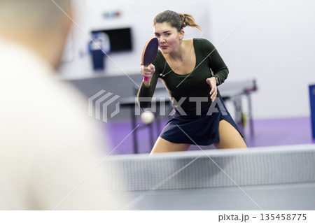 Woman playing table tennis with focus and intensity Woman playing table tennis with focus and intensity 135458775