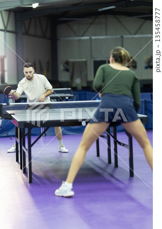 Athletes playing table tennis in an indoor training facility Athletes playing table tennis in an indoor training facility 135458777