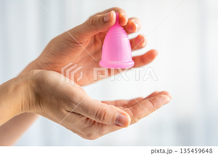 Hands gently holding a pink menstrual cup, symbolizing care, protection, and sustainable feminine hygiene. Concept of eco-friendly period product and body positivity. Hands gently holding a pink menstrual cup, symbolizing care, protection, and sustainable feminine hygiene. Concept of eco-friendly period product and body positivity. 135459648