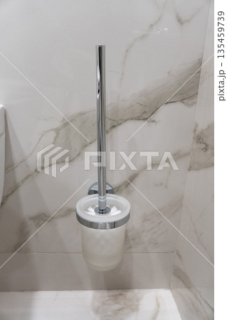 Minimalist toilet brush with holder mounted on a marble bathroom wall, chrome handle and clean modern design 135459739