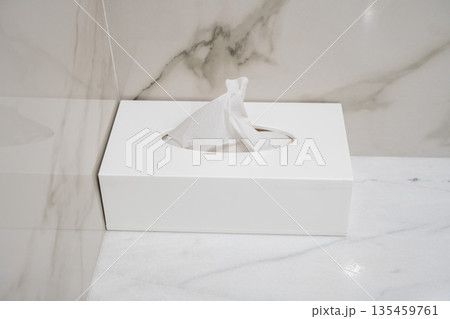 Minimal white tissue box with paper napkin on marble bathroom countertop in modern hotel interior 135459761