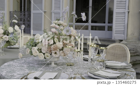 Elegant wedding table setting with flower centerpiece in front of villa. Action Elegant wedding table setting with flower centerpiece in front of villa. Action 135460275