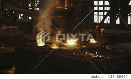 Steelworkers pouring molten metal in foundry. Stock clip 135460433