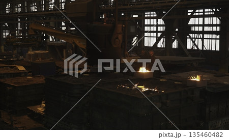 Foundry workers pouring molten metal into molds in industrial plant. Stock clip 135460482