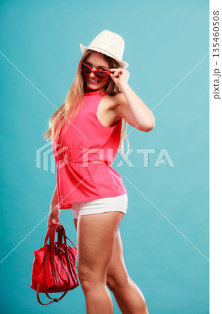 Woman in hat sunglasses and red shirt with handbag 135460508