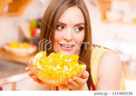Woman holds bowl full of sliced orange fruits 135460536