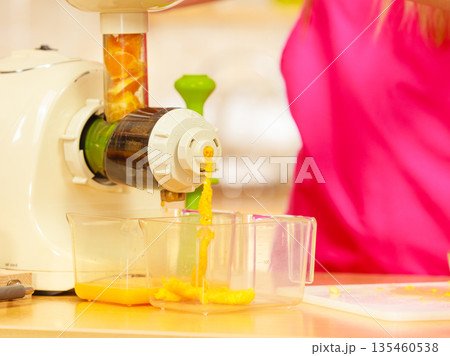 Making orange juice in juicer machine in kitchen Making orange juice in juicer machine in kitchen 135460538