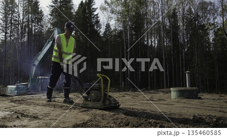 Construction worker compacting soil with vibratory plate compactor. Clip Construction worker compacting soil with vibratory plate compactor. Clip 135460585