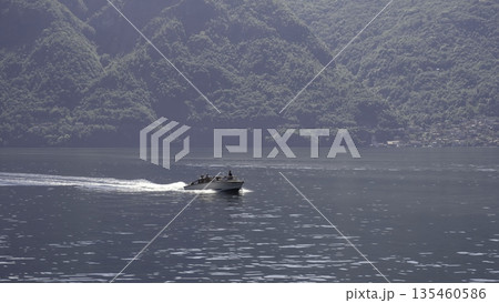 Enjoy a scenic boat ride on calm waters, surrounded by beautiful green mountains. Action 135460586