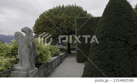 A Beautiful Garden Pathway adorned with a Stunning Sculpture and Lush Greenery all around. Action 135460599