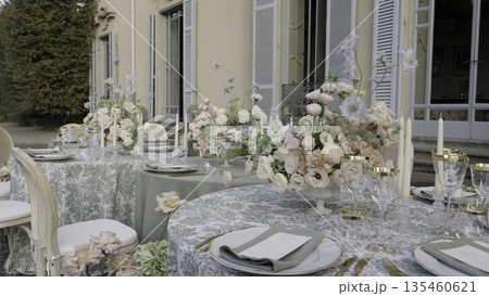 Elegant wedding reception table setting with floral centerpiece in a villa garden. Action 135460621
