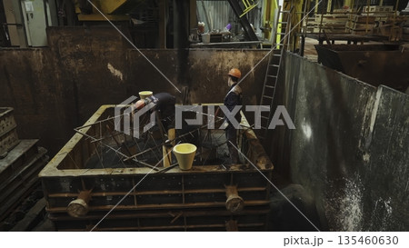 Foundry workers pouring molten metal into mold. Stock clip 135460630