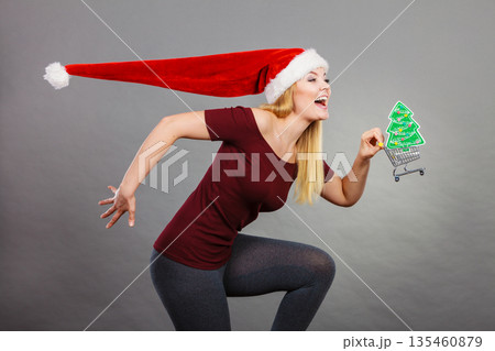 Santa woman holding shopping cart with christmas gifts 135460879