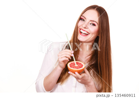 Woman holds grapefruit drinking juice from fruit 135460911