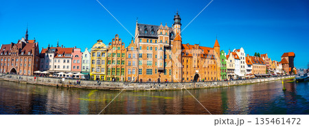 Charming historic architecture lines the waterfront of Gdansk under a clear blue sky. The river is bustling with boats, offering a vibrant scene with the city's iconic brick buildings Charming historic architecture lines the waterfront of Gdansk under a clear blue sky. The river is bustling with boats, offering a vibrant scene with the city's iconic brick buildings 135461472