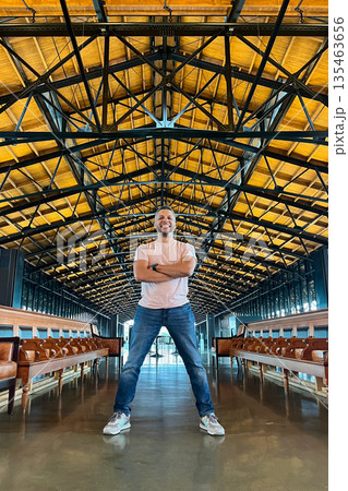 A man stands in a large room with a wooden ceiling 135463656
