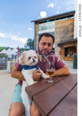 A man sits at a table with a dog on his lap A man sits at a table with a dog on his lap 135463660