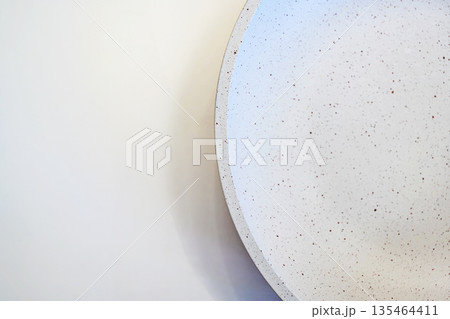 A top-down view of a modern white ceramic bowl with brown speckles, set against a clean off-white background. Perfect for minimalist food photography or lifestyle backgrounds 135464411