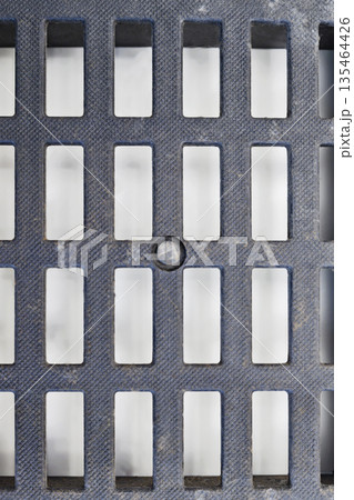 Detailed shot of a textured dark grey plastic ventilation grid with rectangular openings. The surface has a fine pattern and some dust, showing geometric industrial design Detailed shot of a textured dark grey plastic ventilation grid with rectangular openings. The surface has a fine pattern and some dust, showing geometric industrial design 135464426