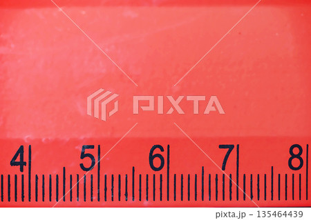 Detailed macro view of a bright red plastic ruler with black markings and numbers from four to eight. Useful for themes like back to school, math, engineering, or office supplies Detailed macro view of a bright red plastic ruler with black markings and numbers from four to eight. Useful for themes like back to school, math, engineering, or office supplies 135464439