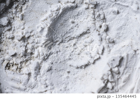 High-resolution macro shot of white powder texture with uneven surface, clumps, and circular patterns. Perfect for abstract backgrounds or representing flour, chalk, or cosmetics 135464445