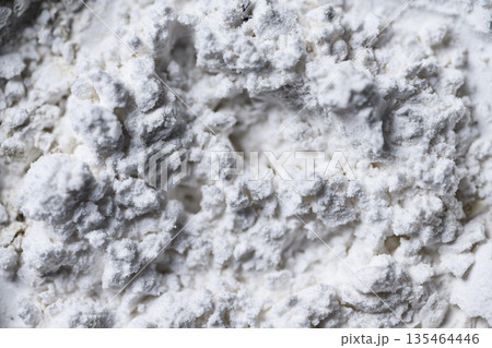 High-resolution macro shot of white powder texture with uneven surface, clumps, and circular patterns. Perfect for abstract backgrounds or representing flour, chalk, or cosmetics 135464446