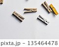 A collection of small natural, white, and yellow wooden clothespins scattered on a white surface, providing ample copy space for text. Perfect for laundry, craft, or office themes 135464478