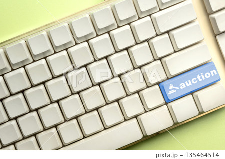 A white computer keyboard featuring a prominent blue 'auction' key with a gavel icon, symbolizing online bidding, digital sales, and internet-based commercial transactions 135464514