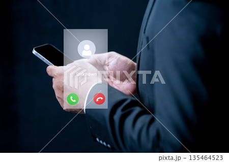 A businessman in a suit holds a smartphone featuring a digital interface for an unknown incoming call. Concept of privacy, communication, and digital security A businessman in a suit holds a smartphone featuring a digital interface for an unknown incoming call. Concept of privacy, communication, and digital security 135464523
